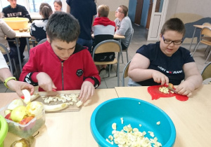 Dominik i Dominik kroją owoce na sałatkę.
