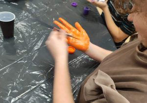 Eliza maluje dłoń na pomarańczowo