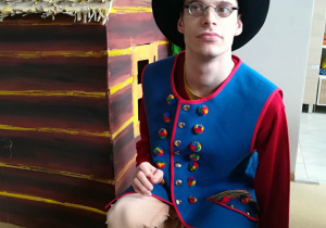 Marcin kuca przy domku podczas zdjęć próbnych w stroju ludowym.