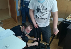 Uczestnicy Programu Rehabilitacja 25 plus montują krzesło.