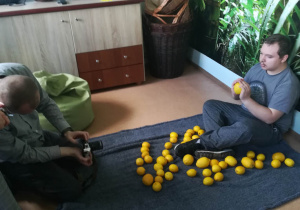 Warsztaty fotograficzne Rehabilitacja 25 plus Damian pozuje do zdjęć z cytrynami podczas sesji.